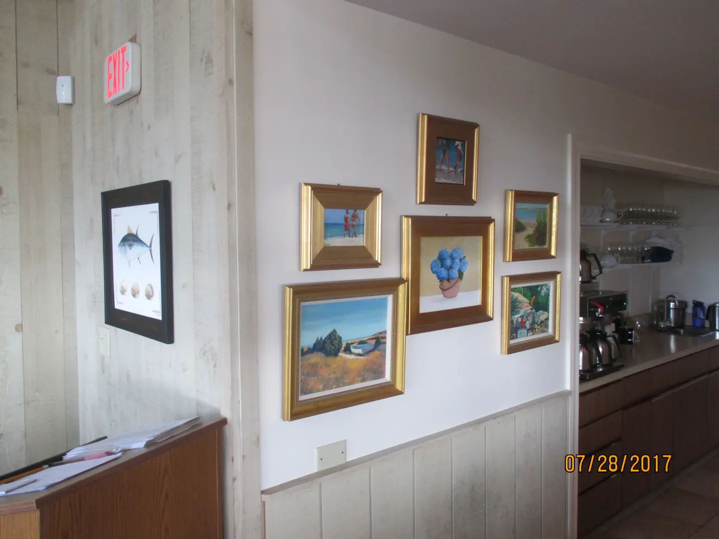 A wall with several paintings hanging on it.