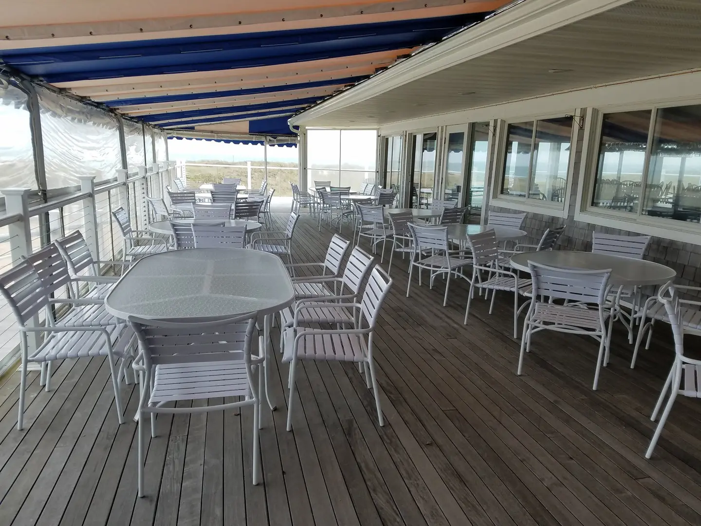 A large wooden deck with tables and chairs.