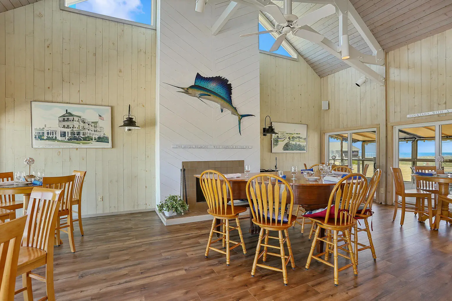 A dining room with wooden chairs and a fish on the wall.