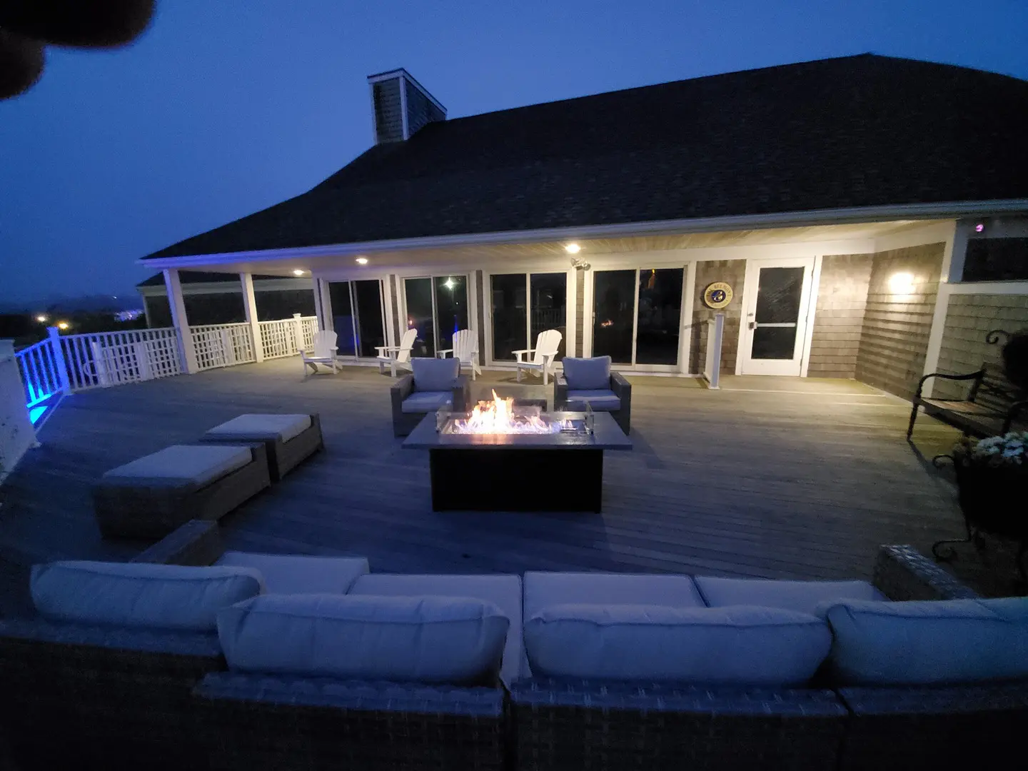 A patio with couches and fire pit at night.
