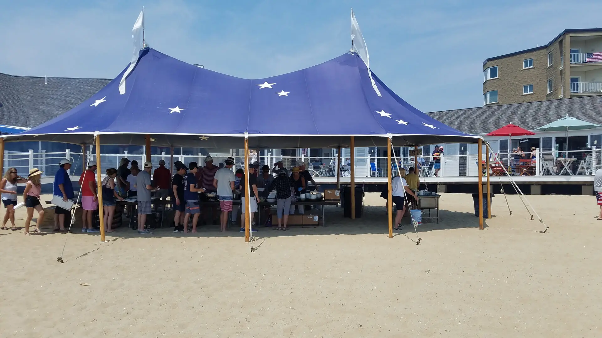 A group of people sitting under an awning on the beach.