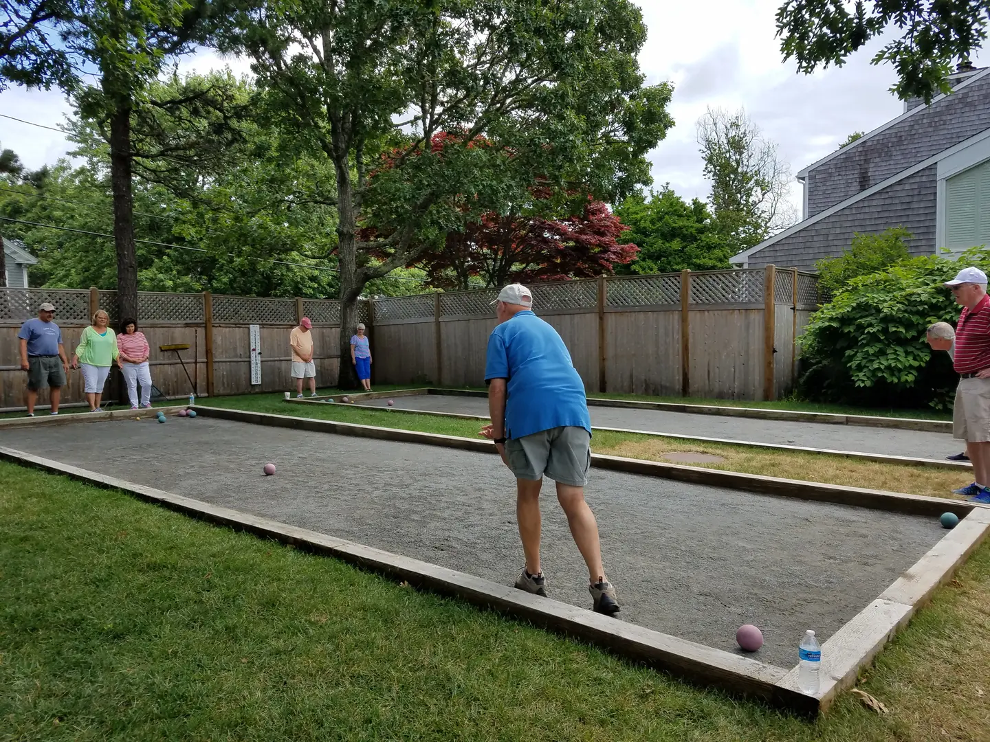 A man playing bocce ball in the backyard.