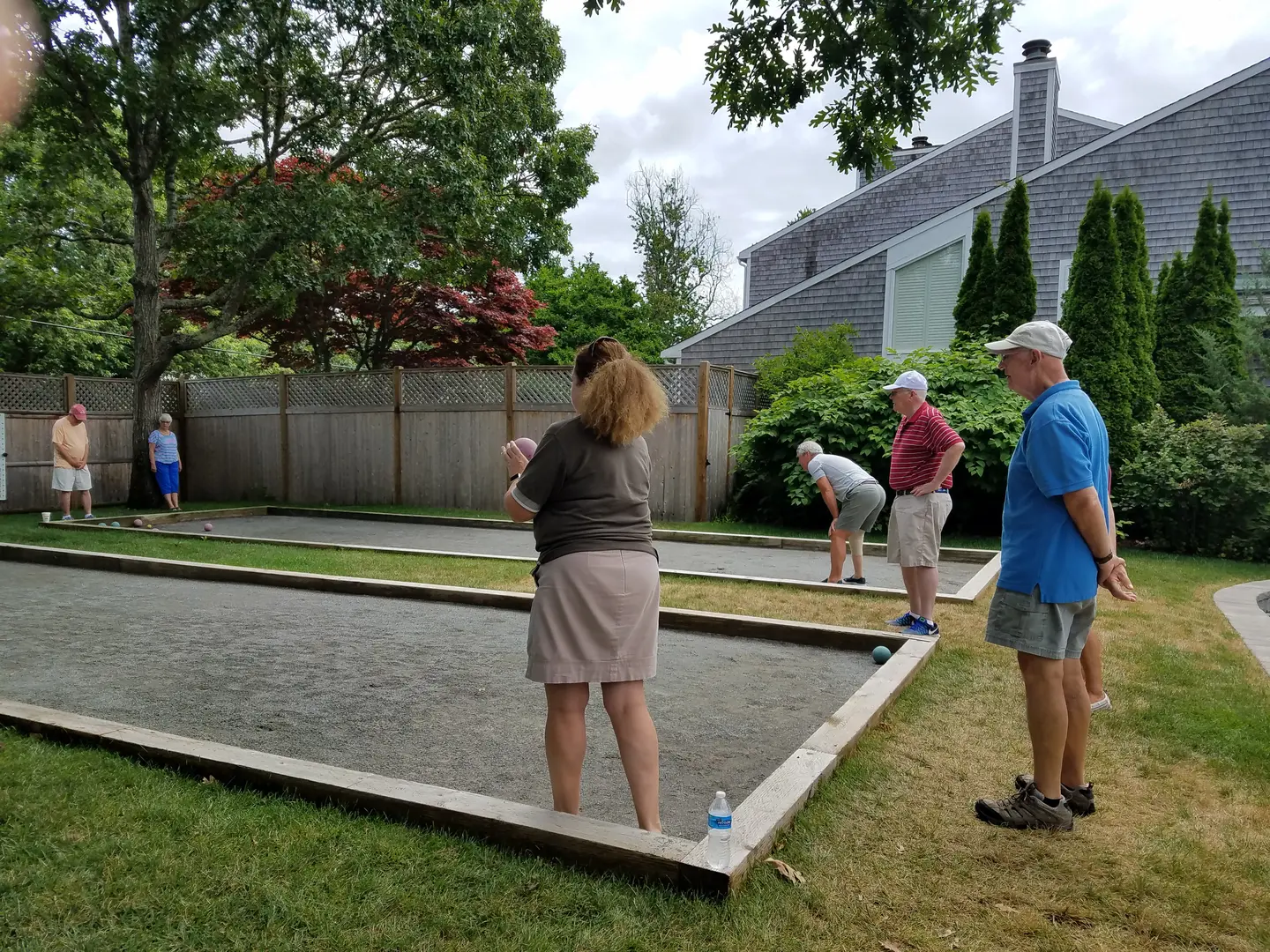 A group of people playing bocce ball in the backyard.