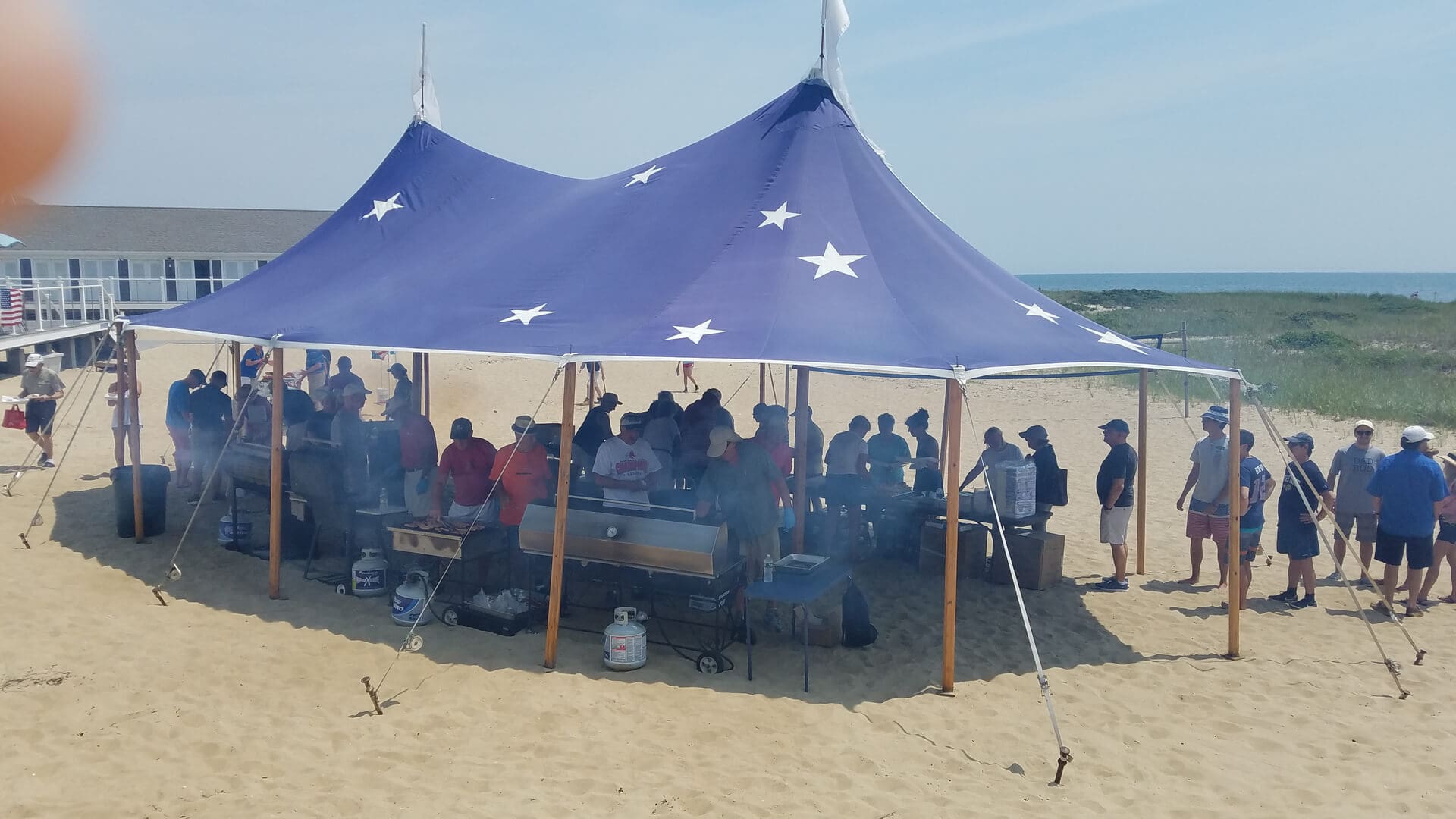 A group of people sitting under a blue tent.