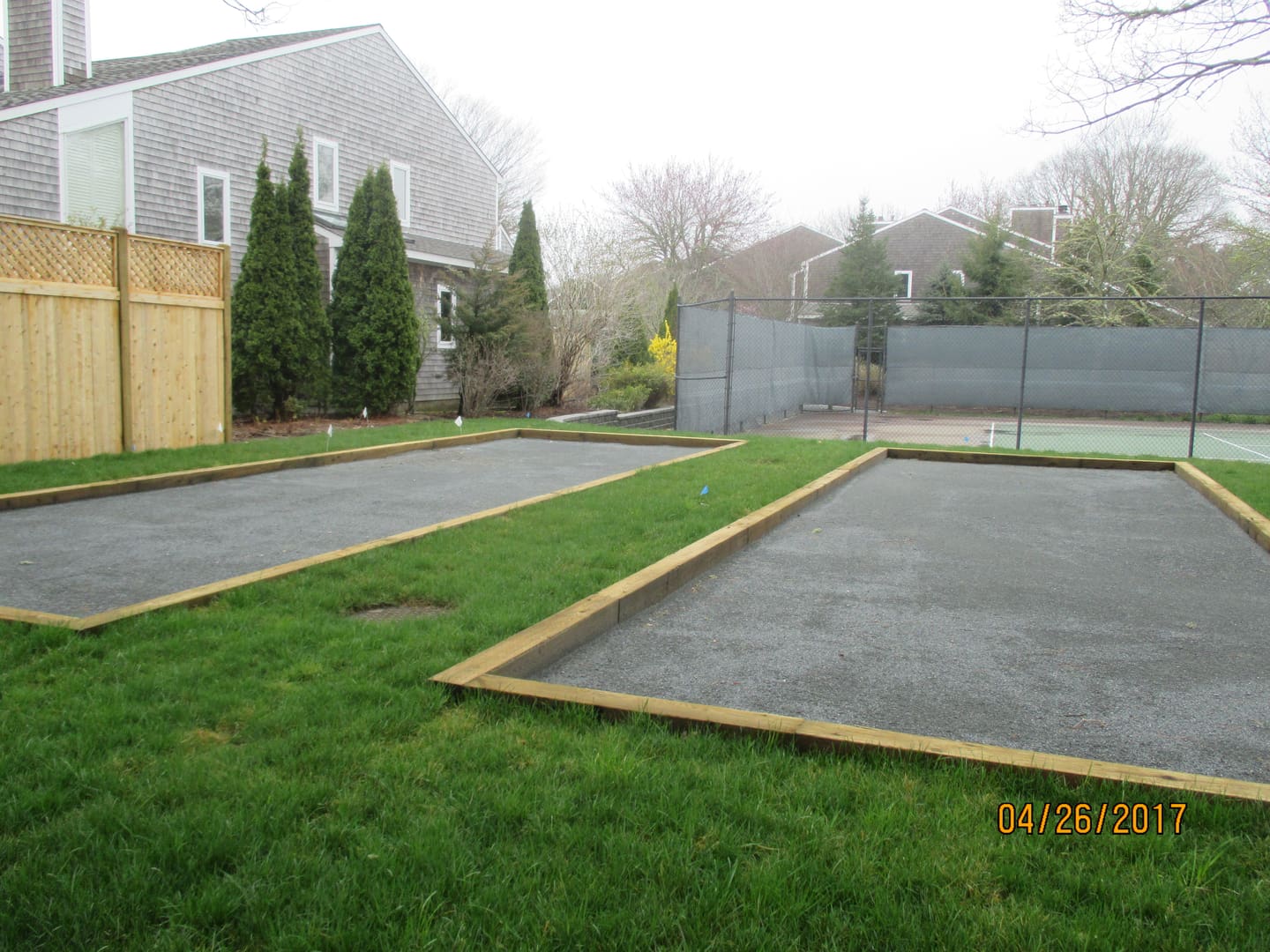 A couple of tennis courts in the middle of a yard.