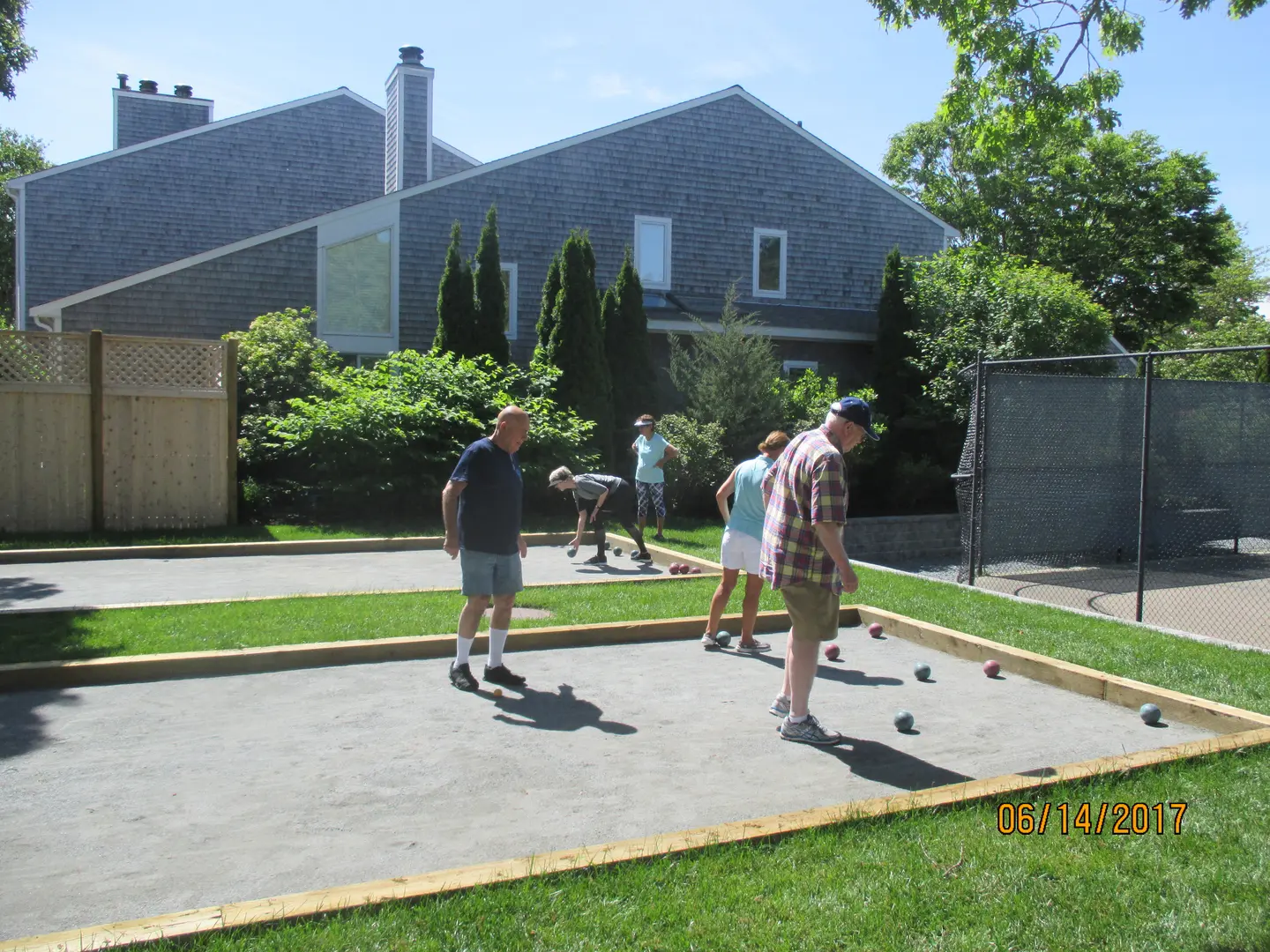 A group of people playing with bowls in the yard.