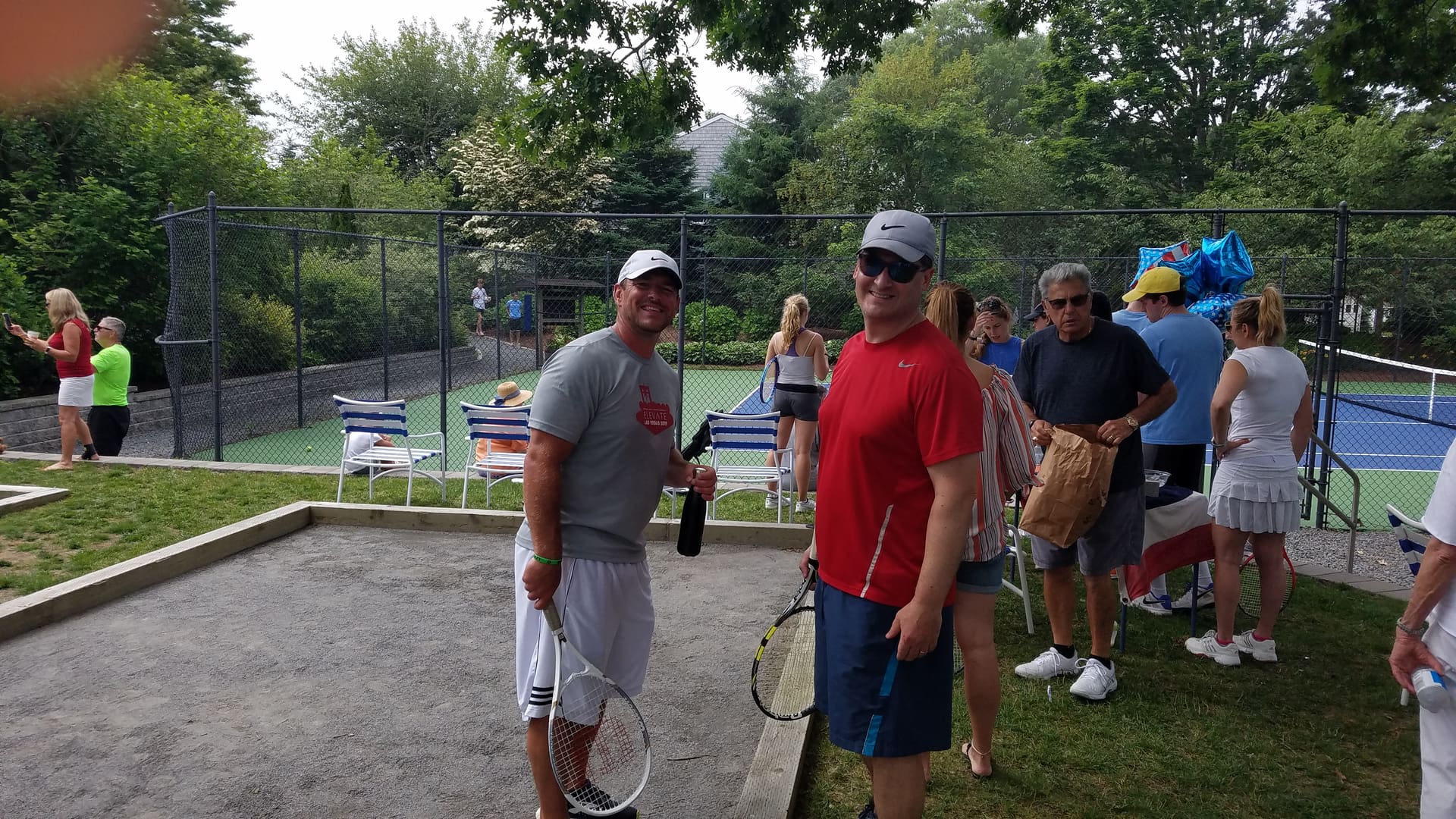 Two men standing next to each other holding tennis rackets.