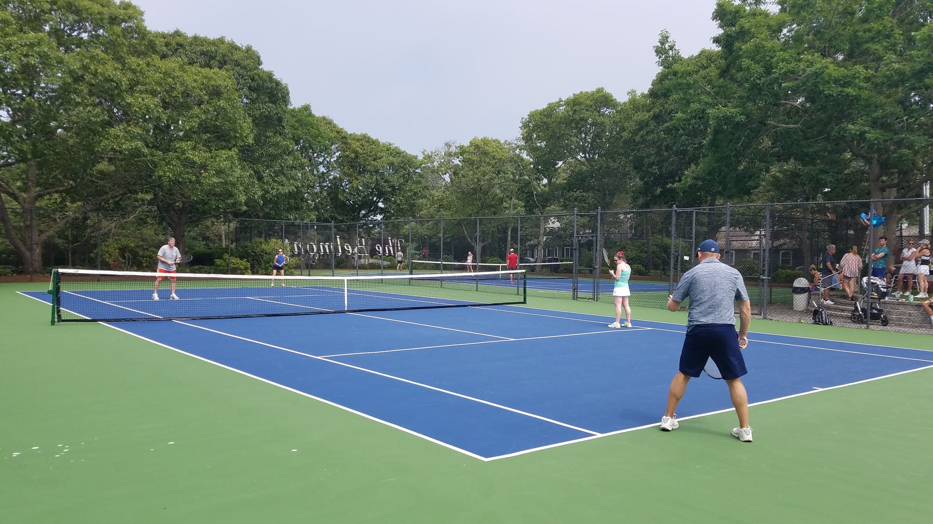 A group of people playing tennis on a blue court.