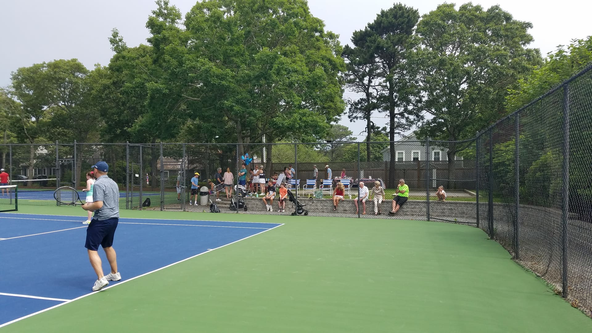 A group of people standing on top of a tennis court.