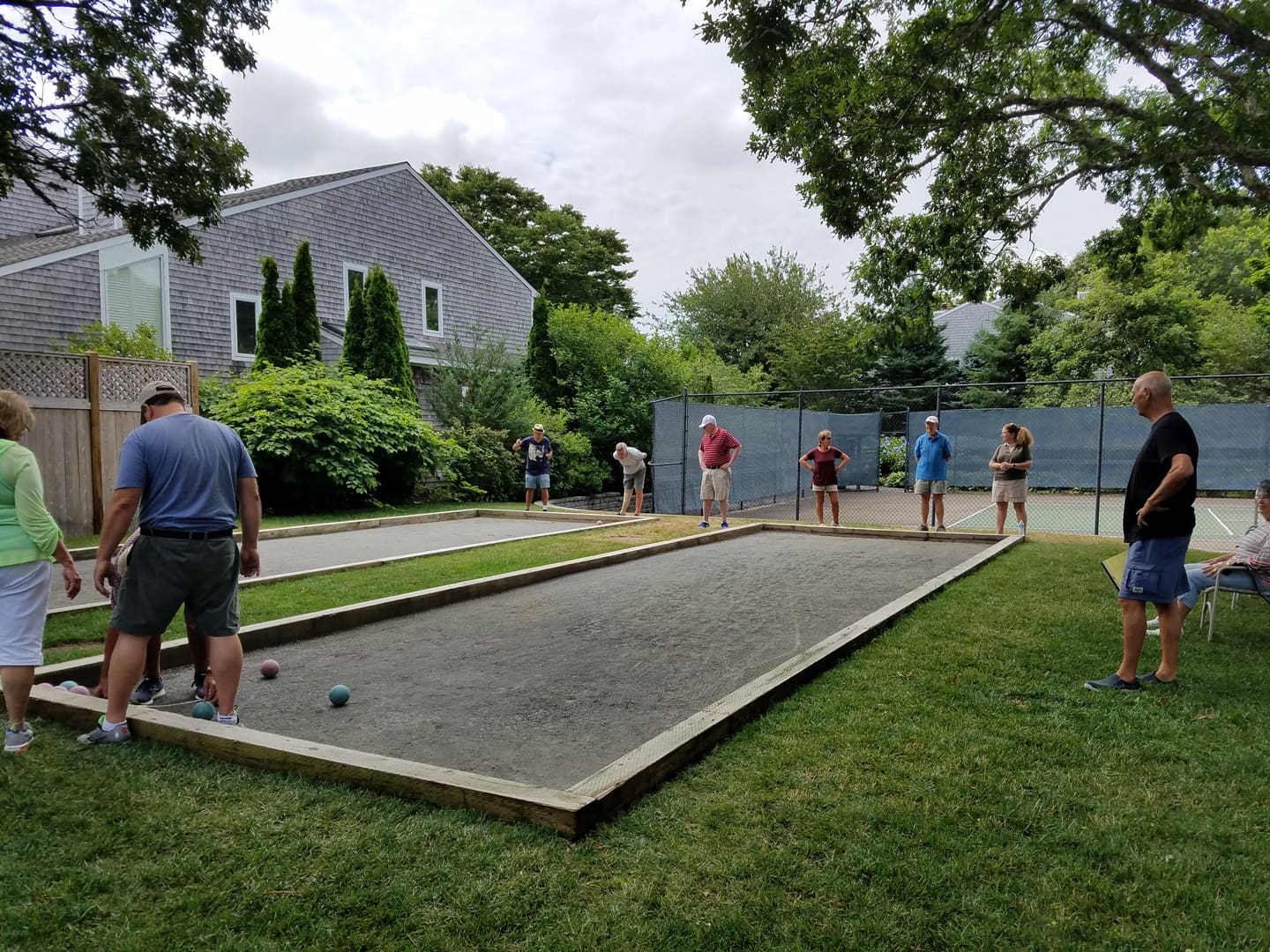A group of people playing bocce ball in the yard.