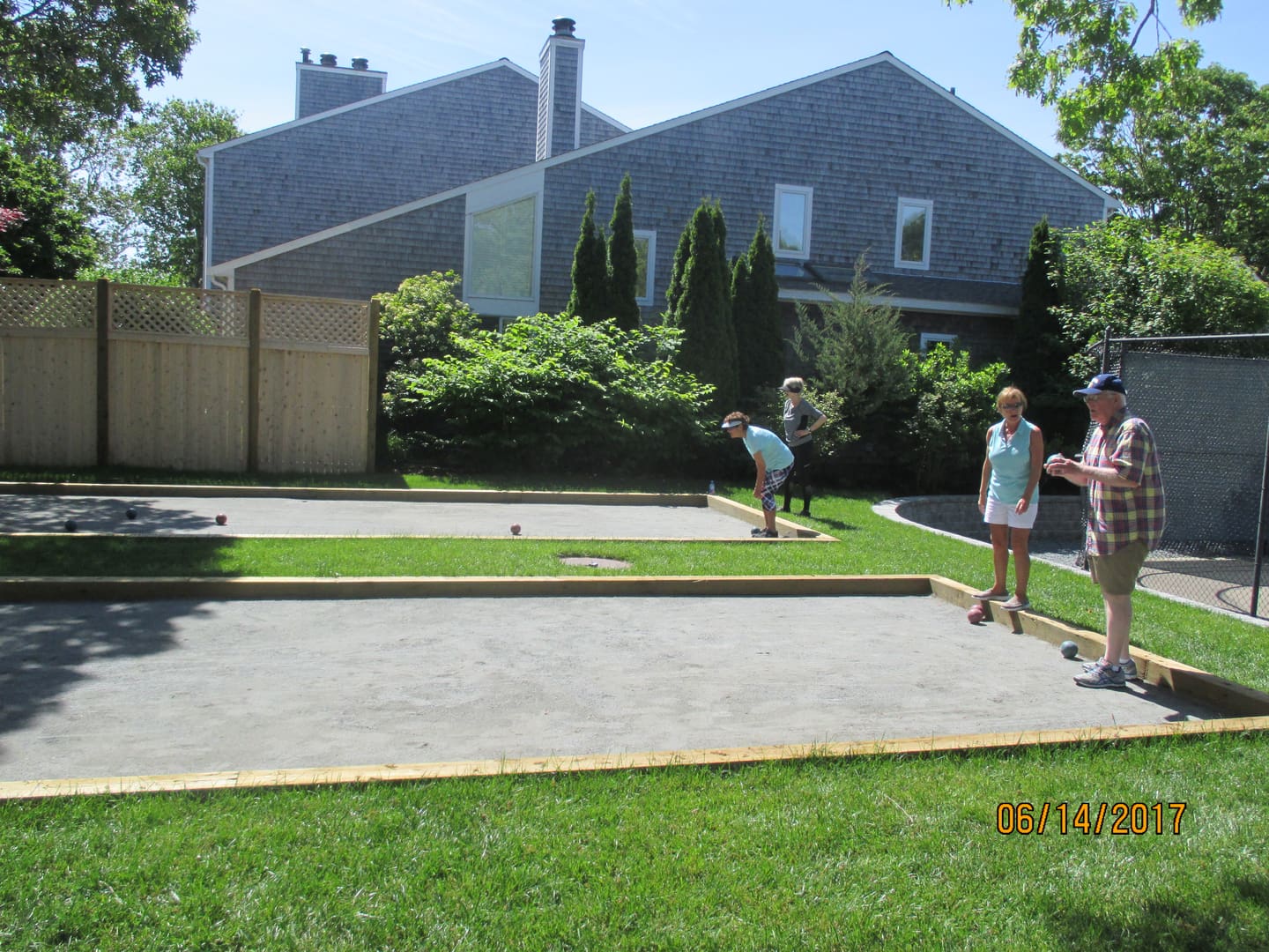 A group of people playing bocce ball in the yard.