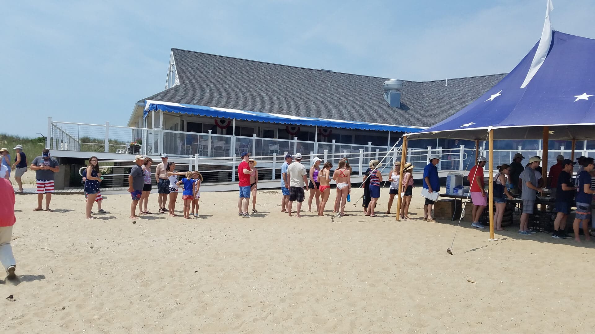 A group of people standing on top of a sandy beach.