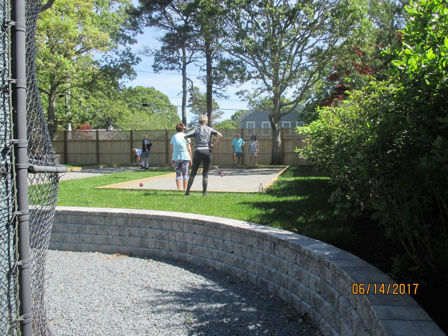 Two people standing on a concrete wall near trees.