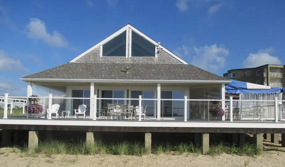 A house with a deck and patio on the beach.