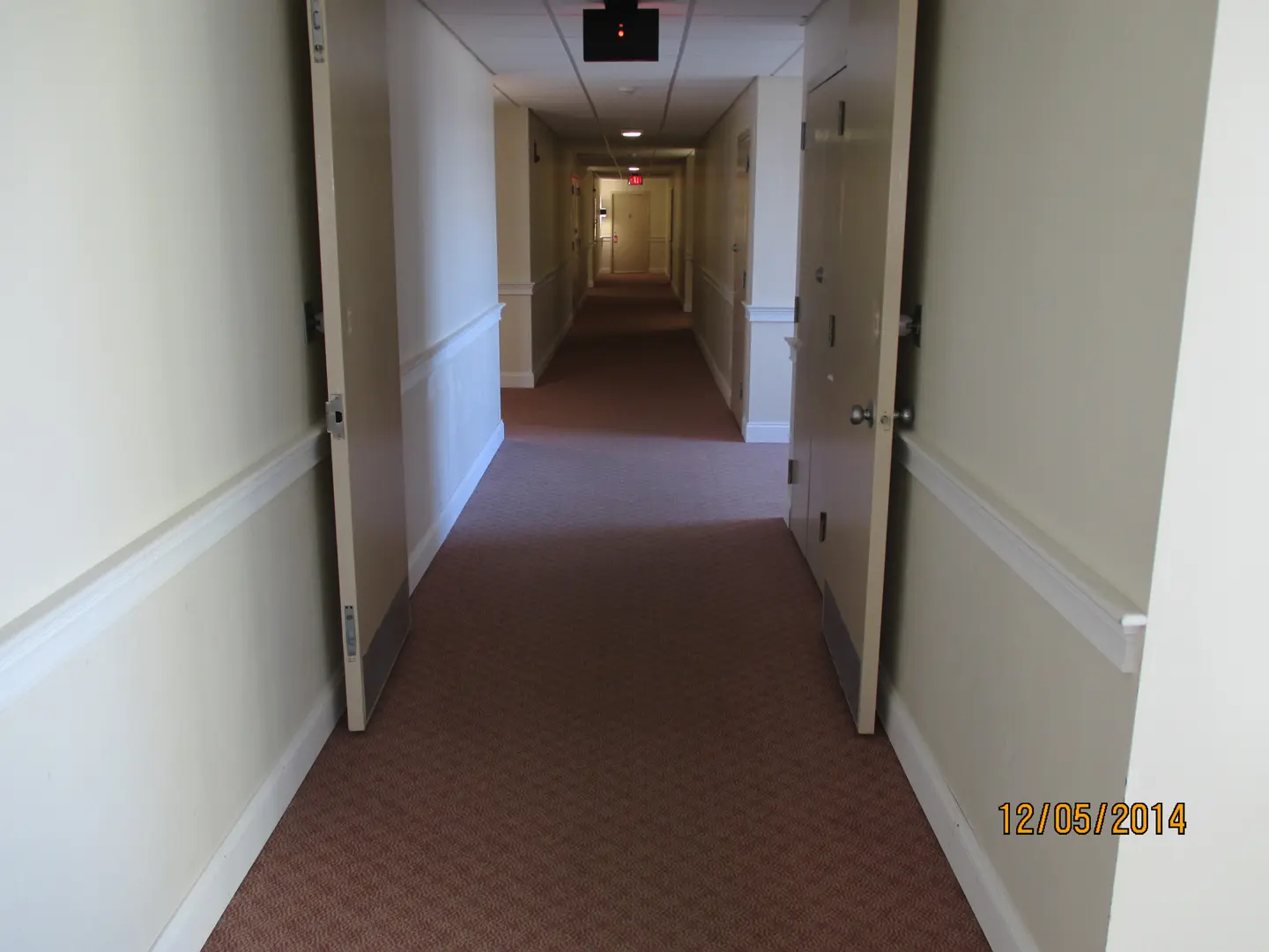 A hallway with two doors and no one in it.