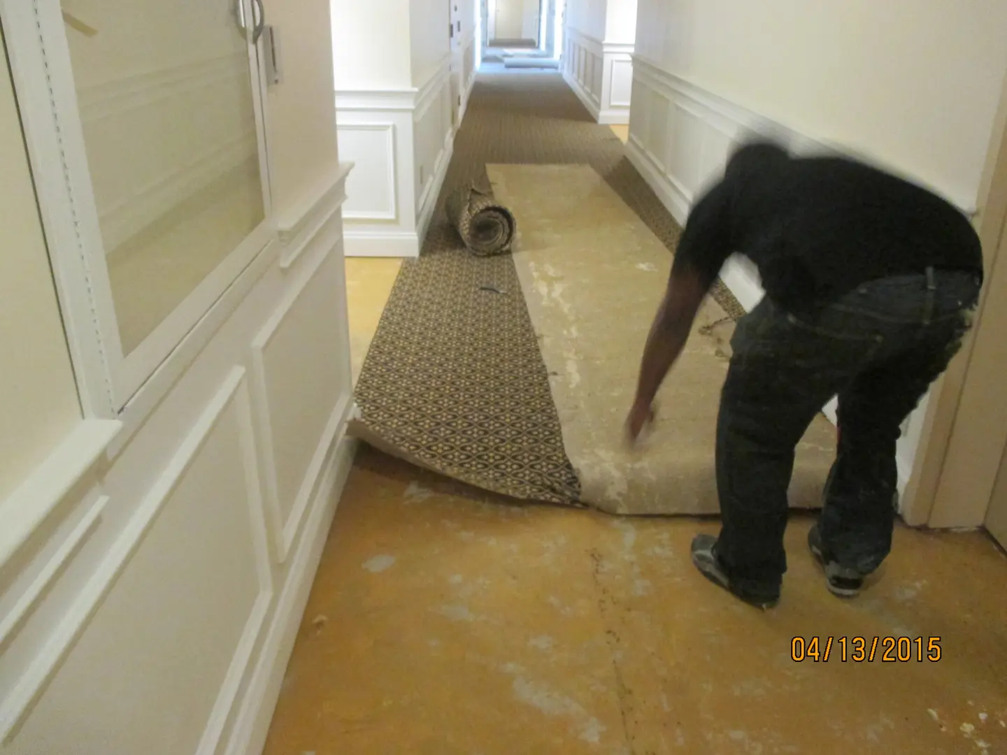 A man is removing carpet from the floor.